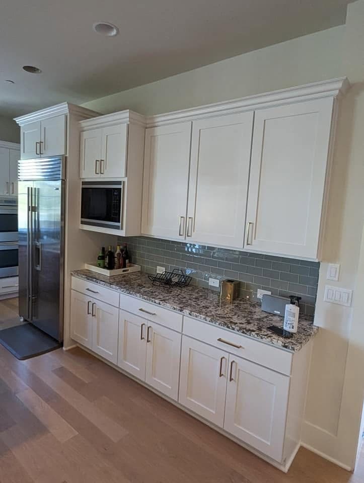 Refinished warm white shaker cabinets with a granite worktop and sage subway tile
