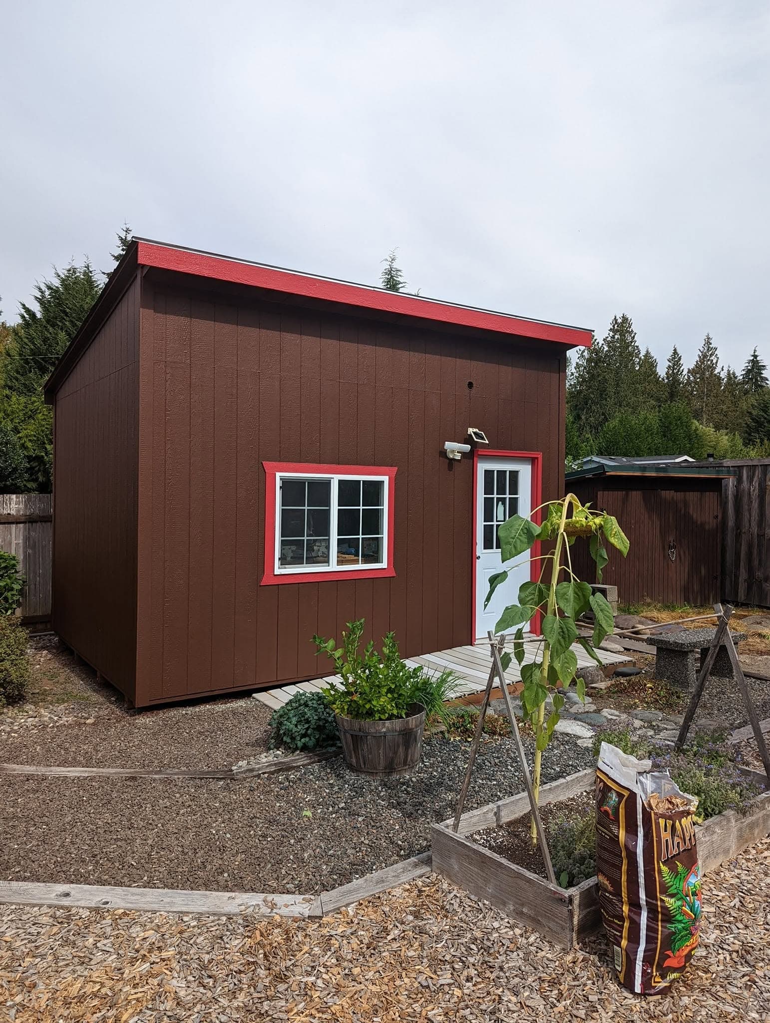 A workshop shed painted deep brown with bright red trim and a white door