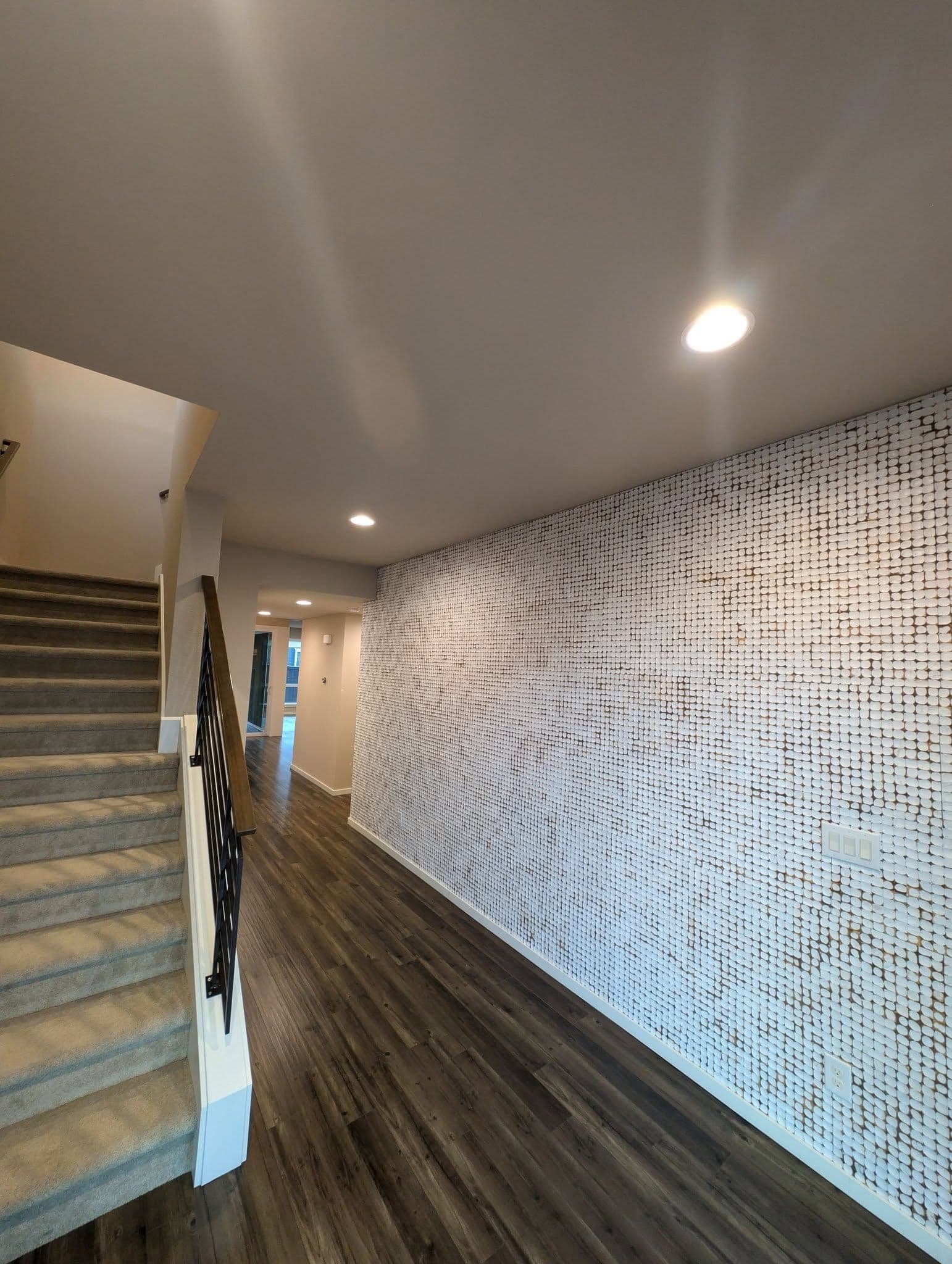 A hallway and stairs with a carpet runner and a full-height textured feature wall