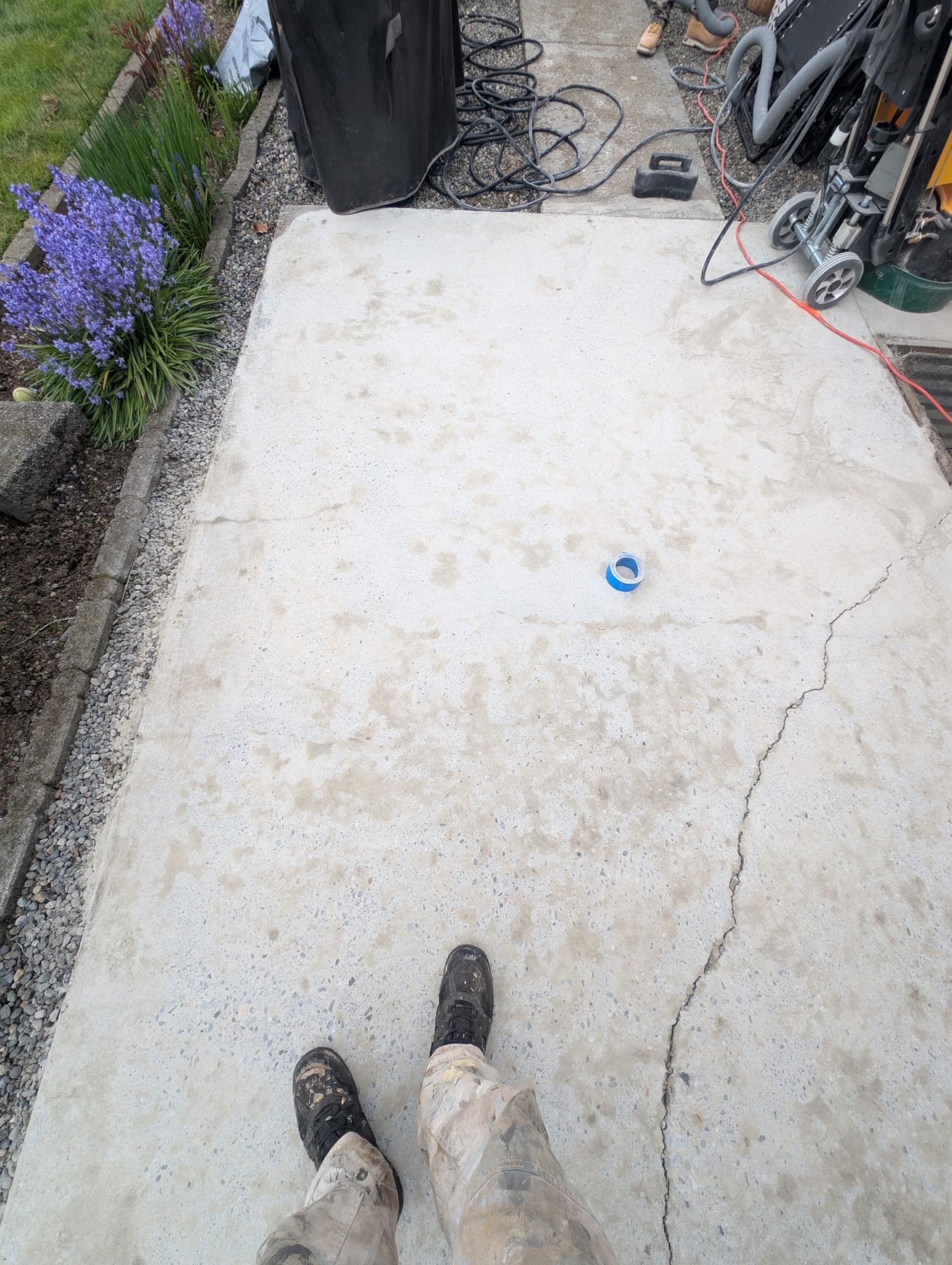 A ground concrete walkway, pale and clean with the aggregate showing, a crack running down one side