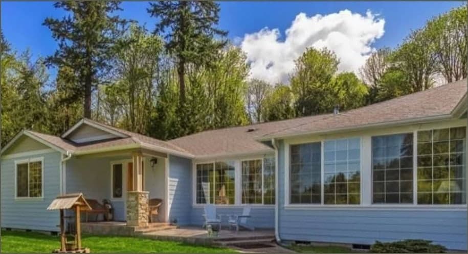 A single-story ranch in pale blue siding with white trim before repainting