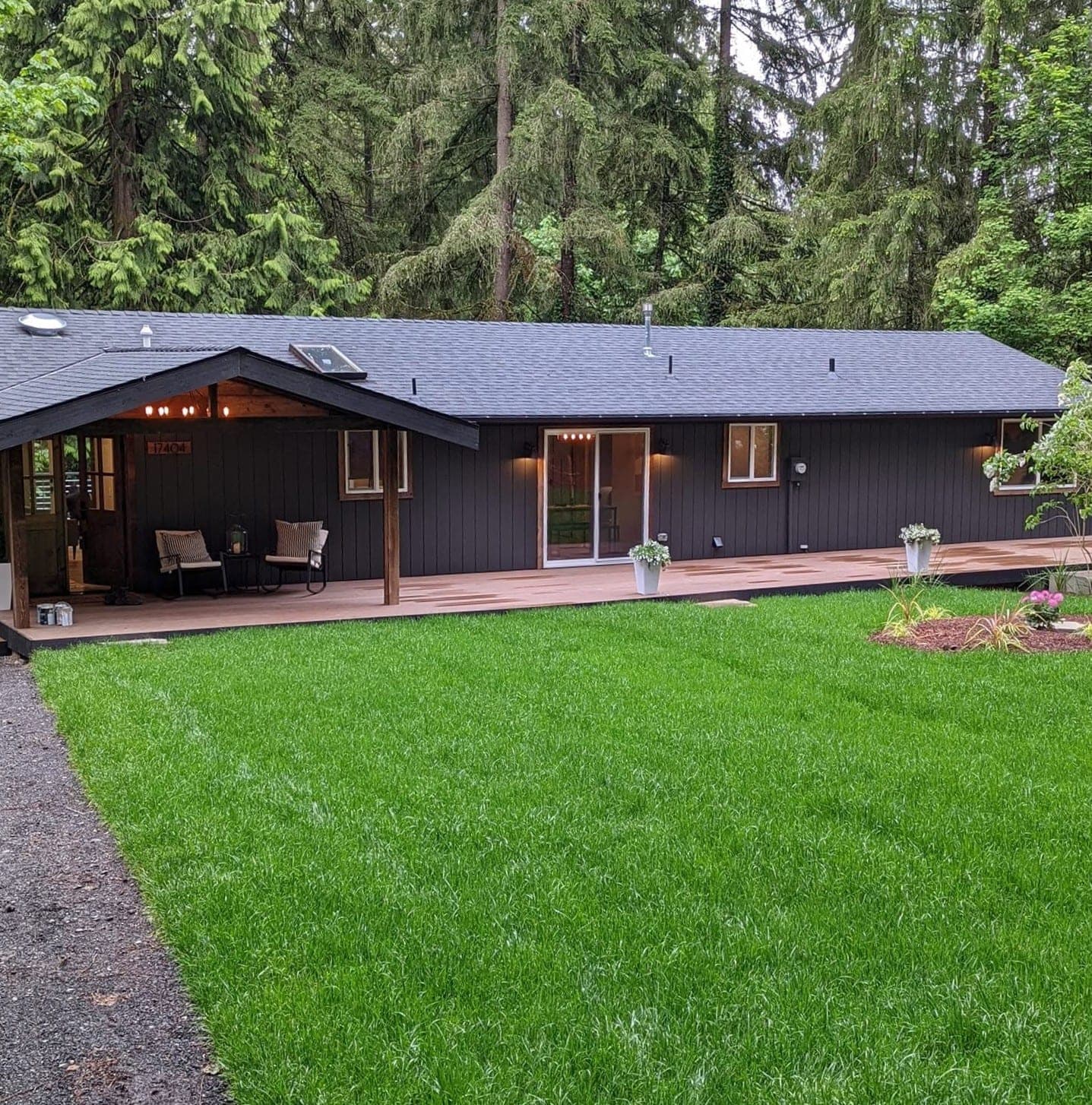 A ranch house finished in deep charcoal board and batten with a warm timber porch