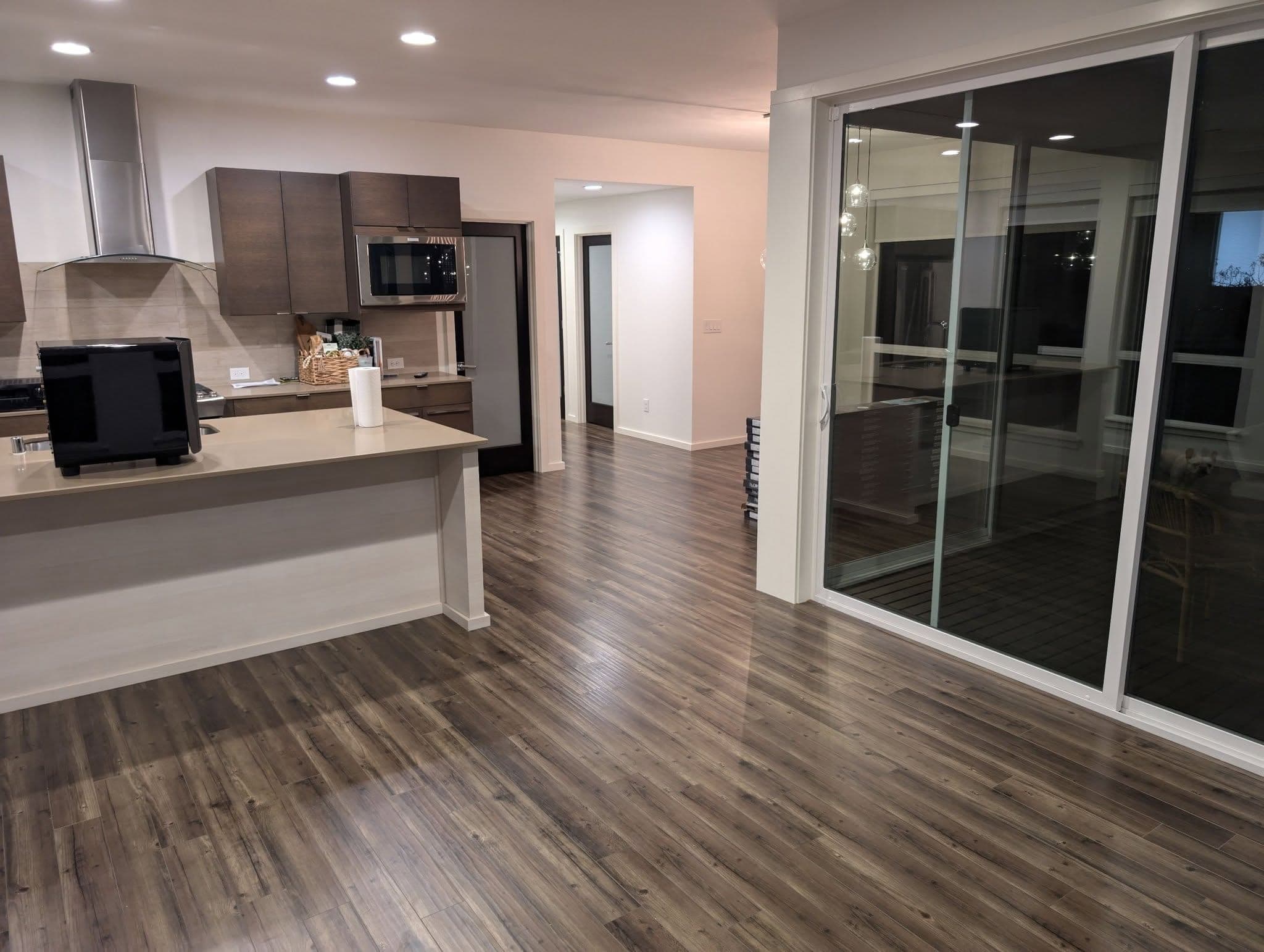 Open plan kitchen and living room in the evening with timber cabinets and dark wood floors