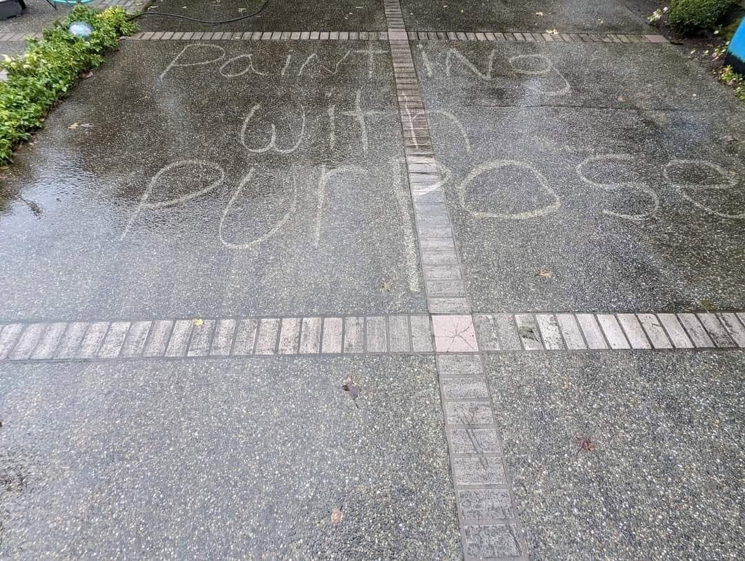 An aggregate driveway half washed, clean concrete on one side and grey on the other